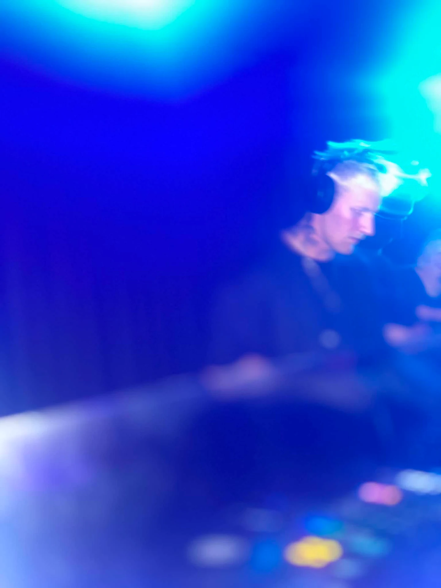 Et sløret foto af Beyorn som DJ i blåt og cyan klublys med lysspor over pulten.