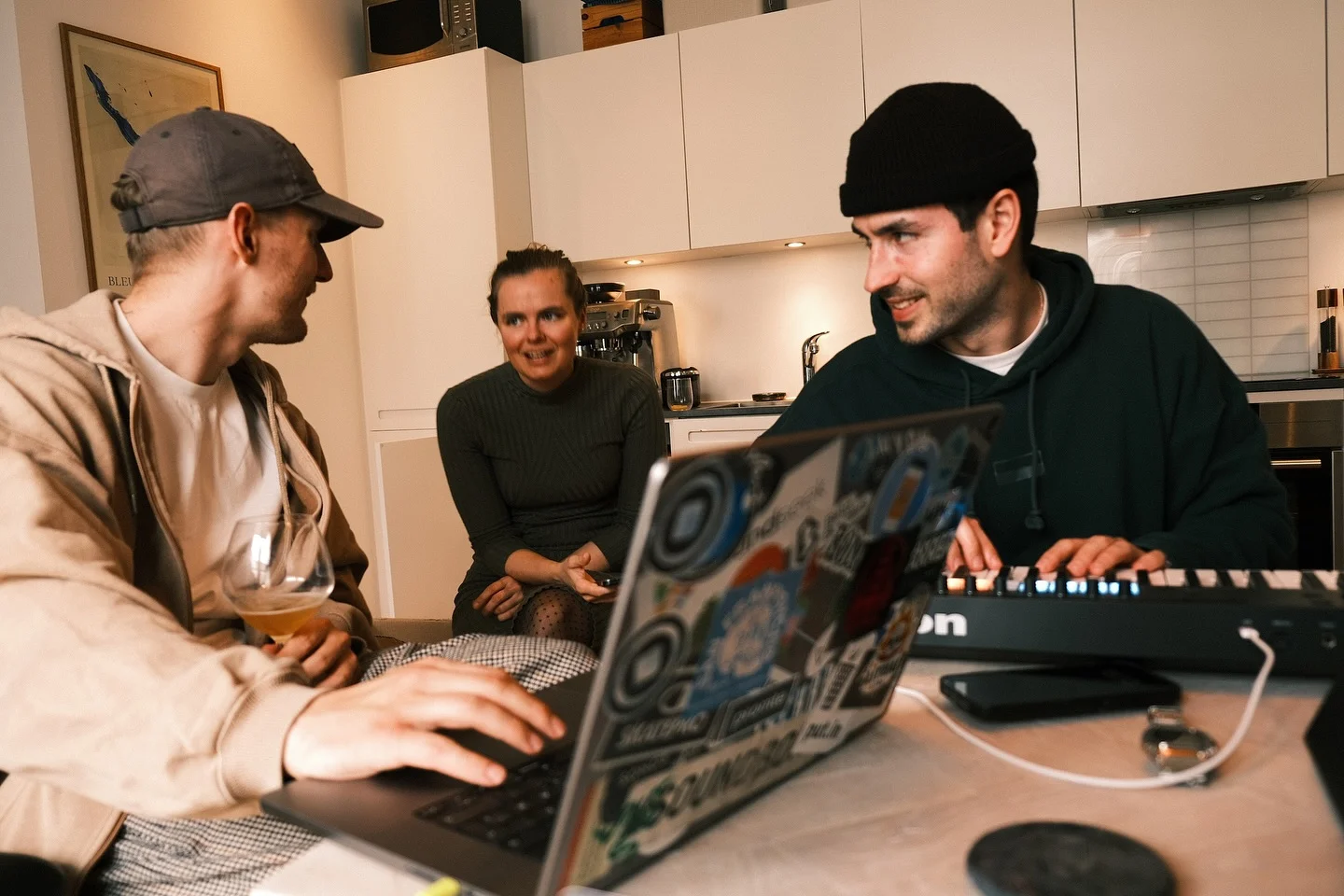 Musik sammen omkring en laptop og et keyboard i et køkken.