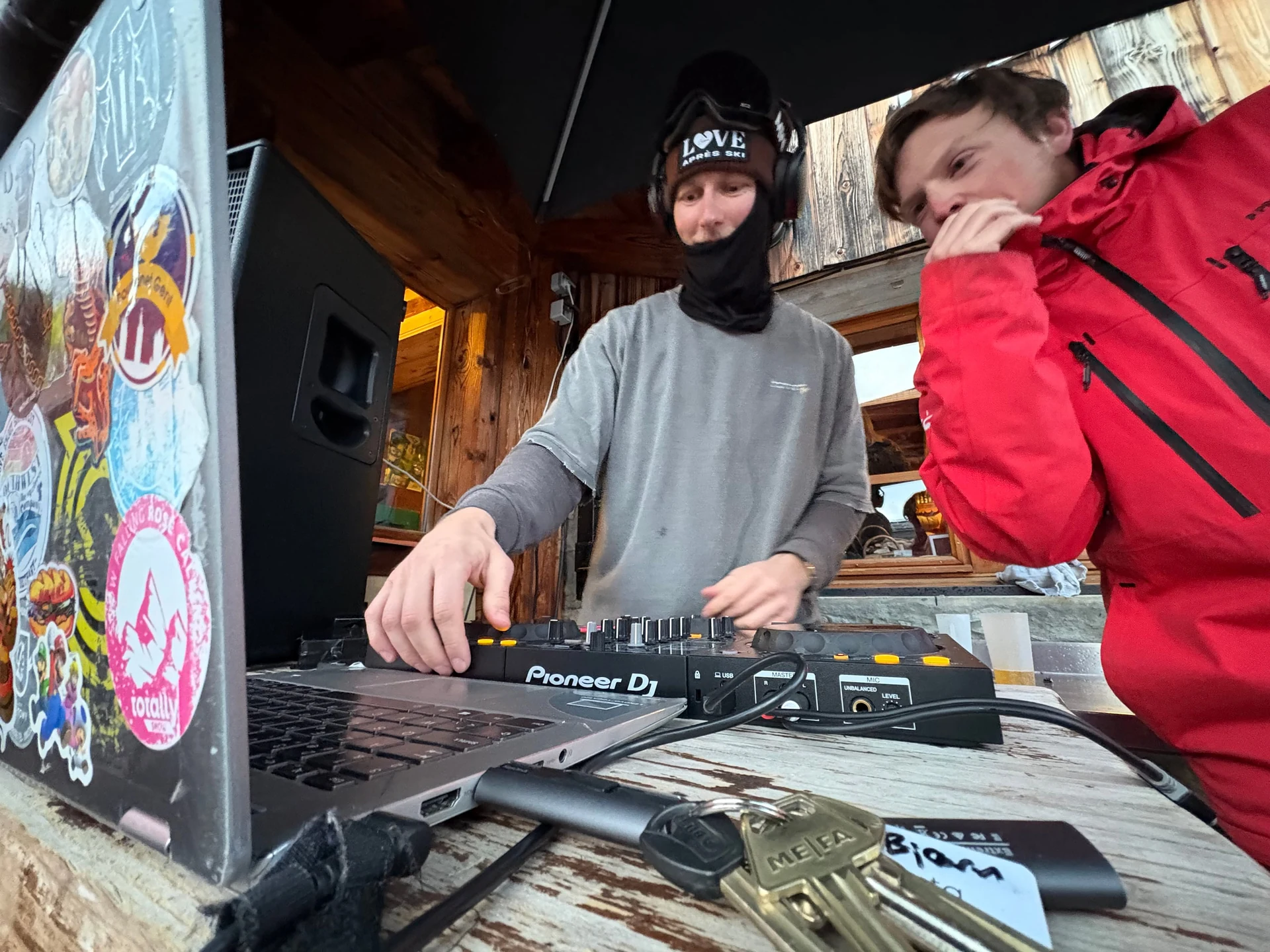 Beyorn med elefanthue og hovedtelefoner som DJ sammen med en ven i en træhytte med laptop og pult.